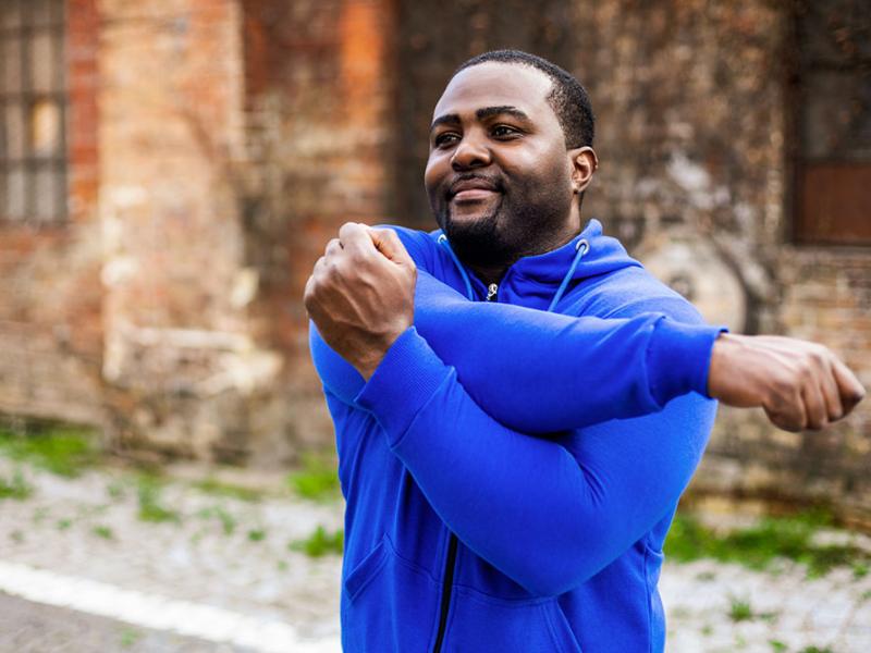 man doing a shoulder stretch outside