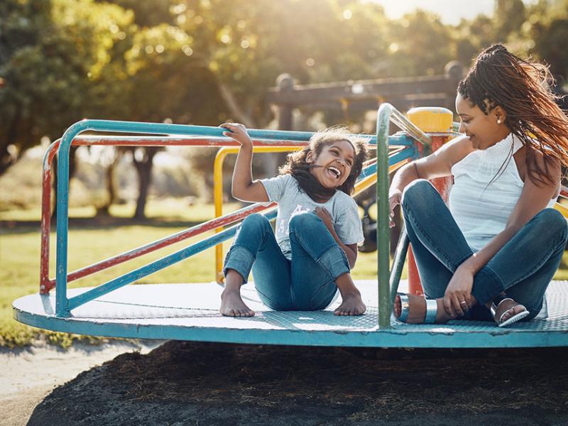 mom and daughter playing on a merry go round