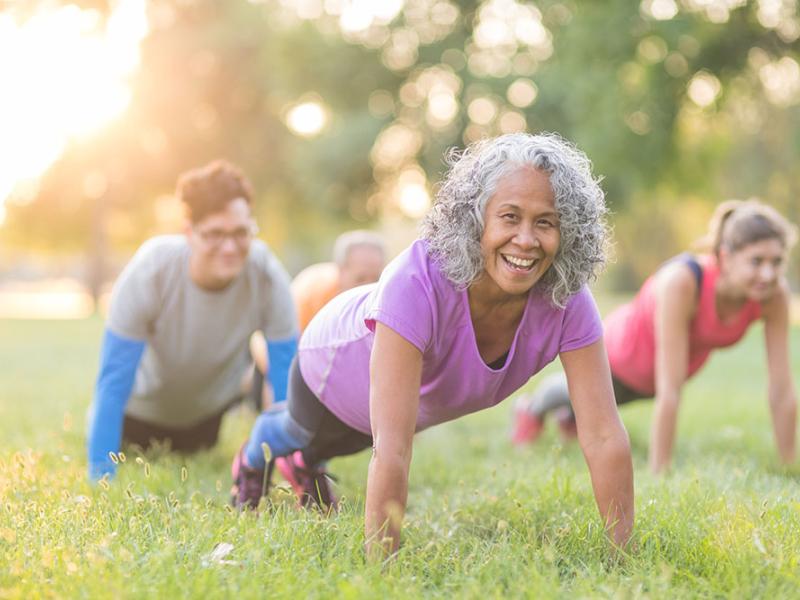 people in plank pose in a class outside at a park