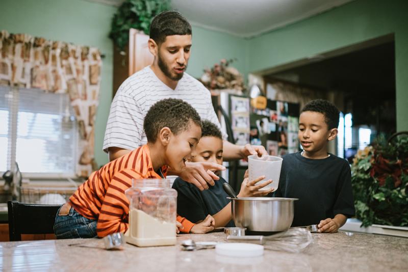 3 boys and father measuring ingredients into a bowl